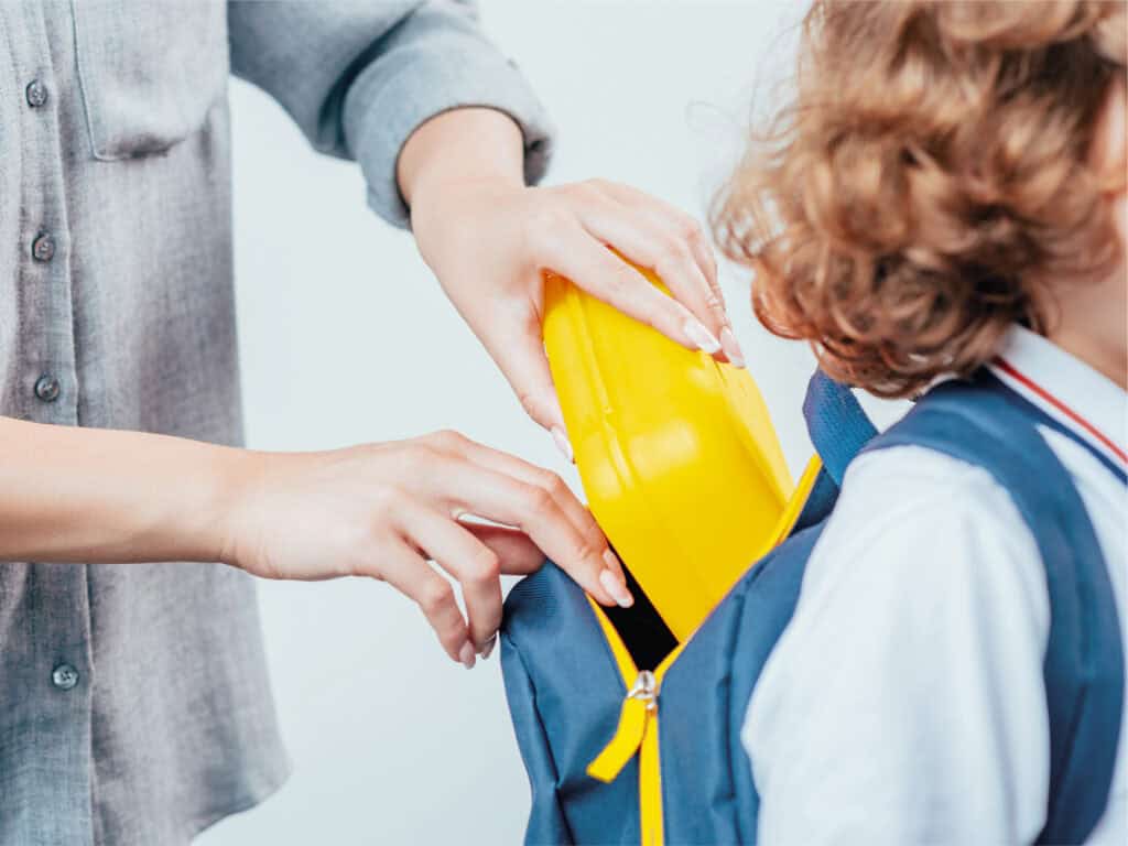 Adult putting lunchbox in child's bag