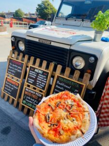 Pizza being held next to pizza truck
